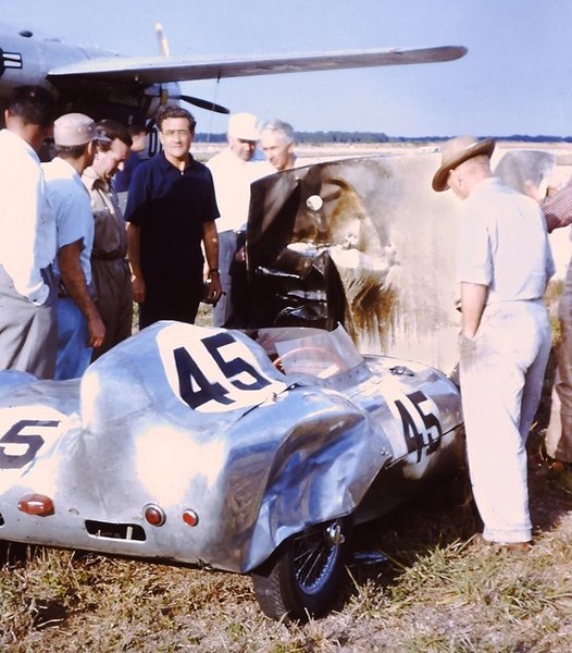 1956 Sebring 12 Hours - Briggs Cunningham (blue shirt), and several race fans, looking over the burned-out engine compartment of Lotus XI he was to take possession of after the race.jpg